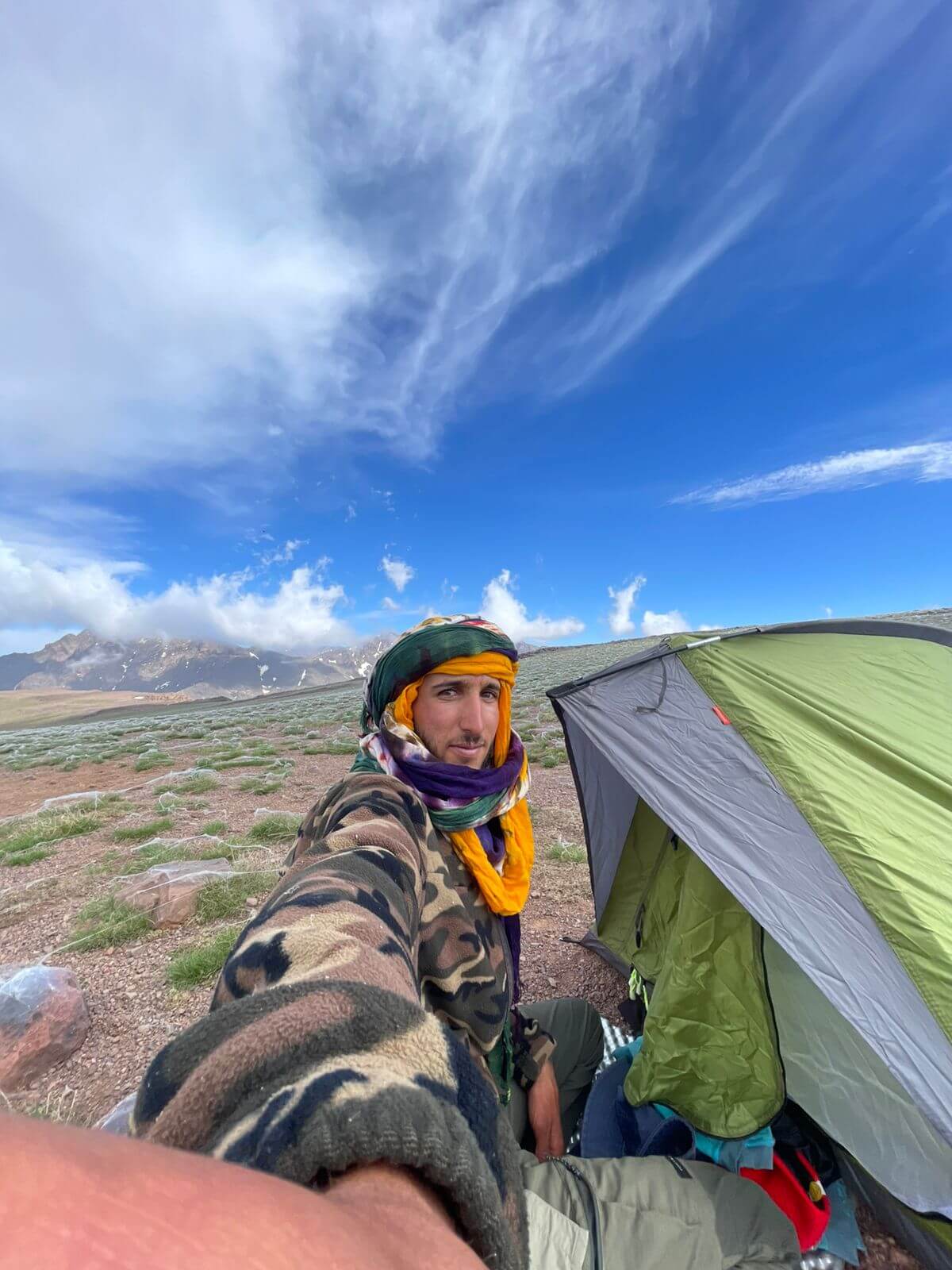 Radouane on a mountain expedition with a tent and backpack